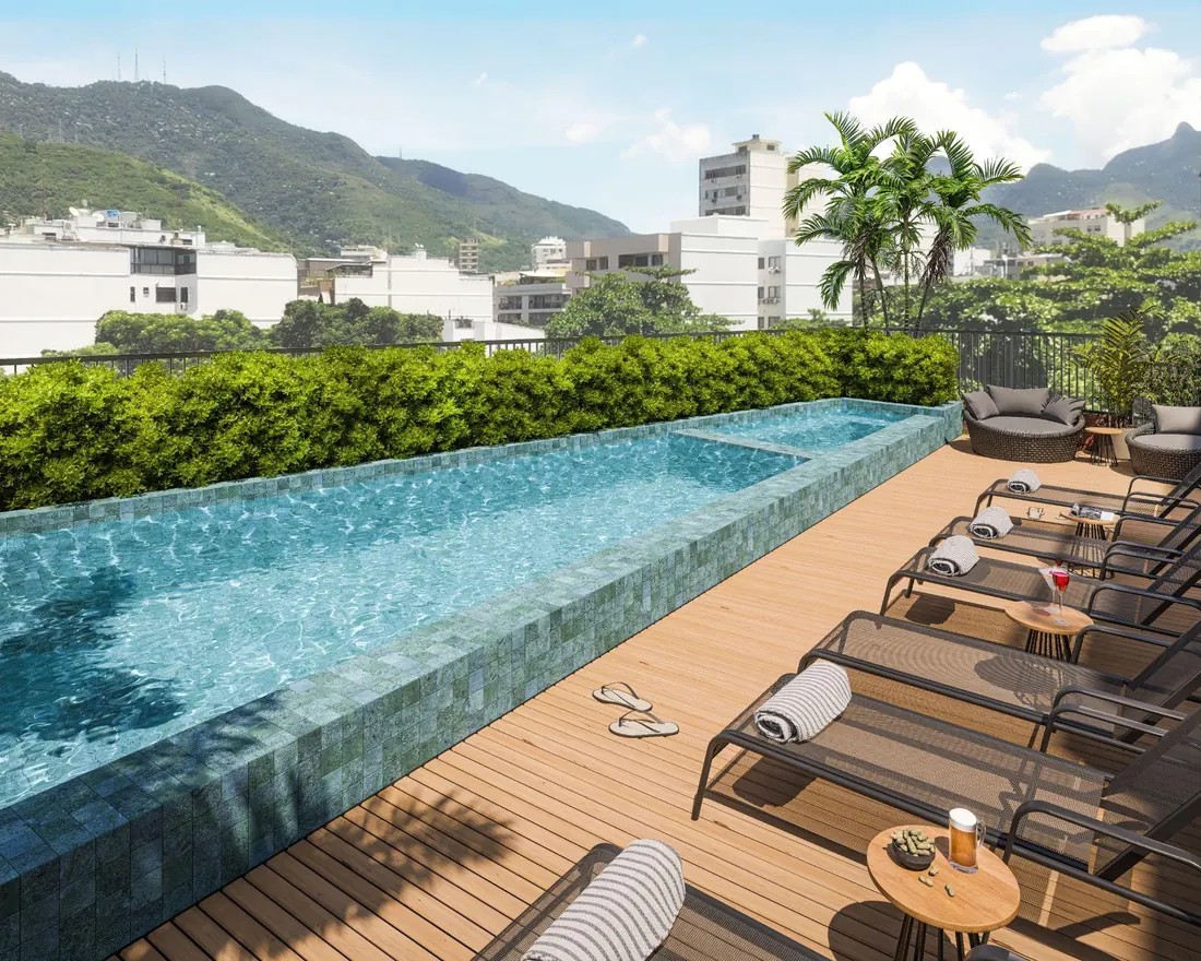 Piscina com deck de madeira e espreguiçadeiras do Cores da Tijuca, com vista para os morros